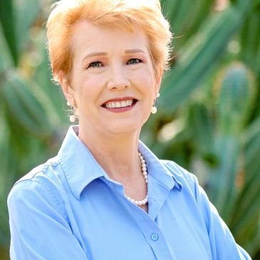 Smiling elderly woman outdoors in blue shirt.