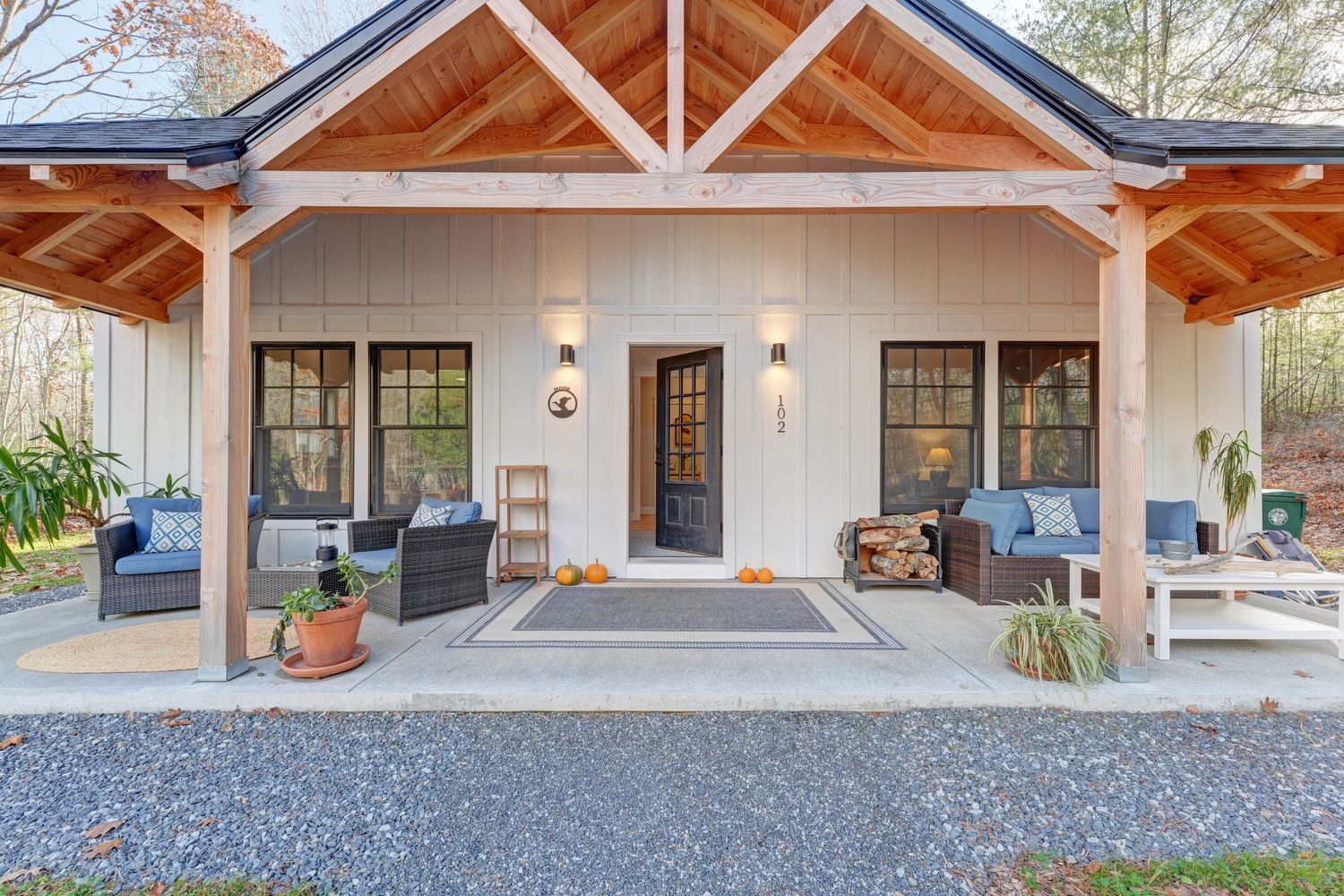 Cozy porch with wicker furniture, blue cushions, and autumn pumpkins.