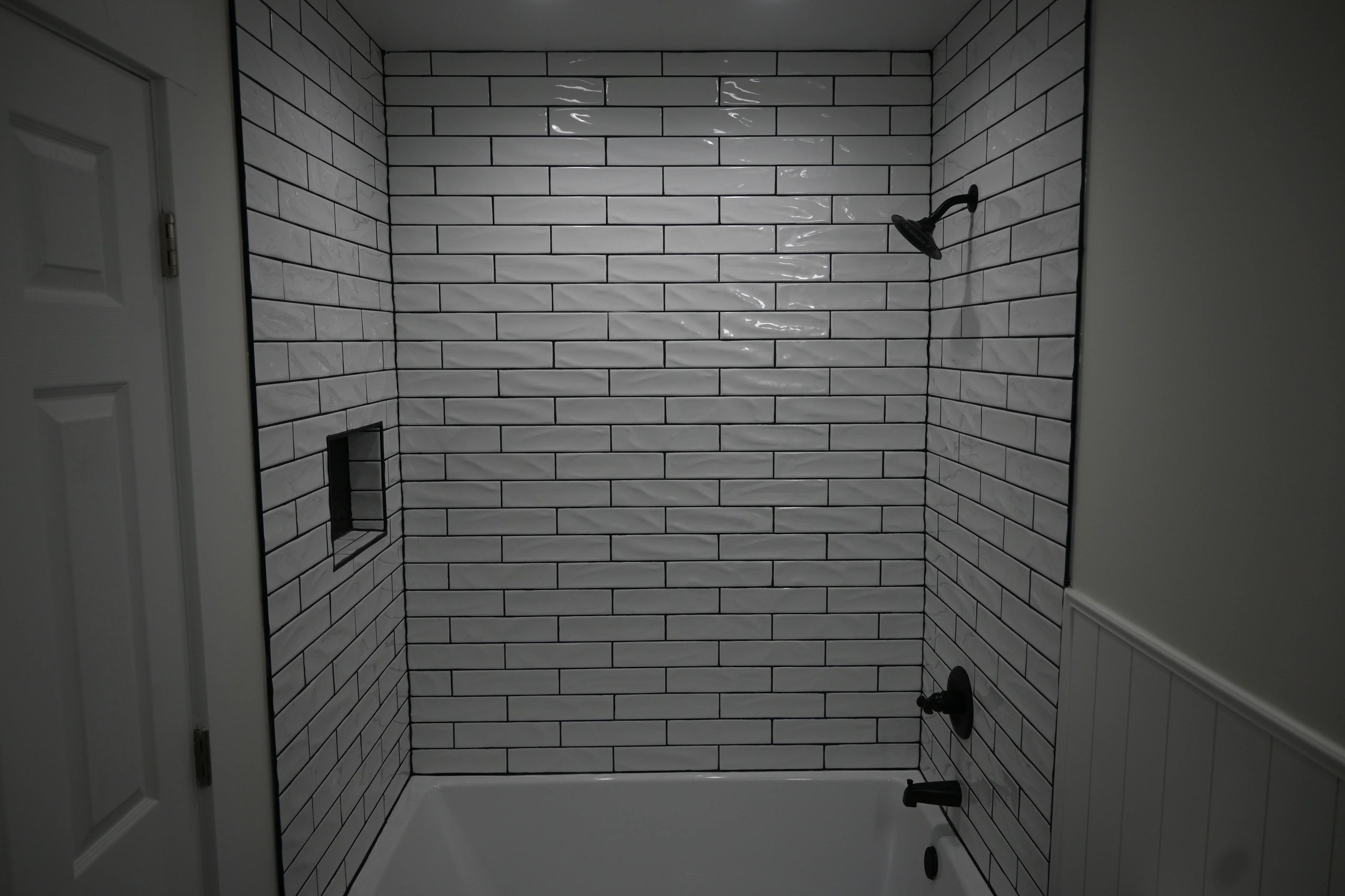 Bathroom shower with white subway tiles and matte black fixtures.