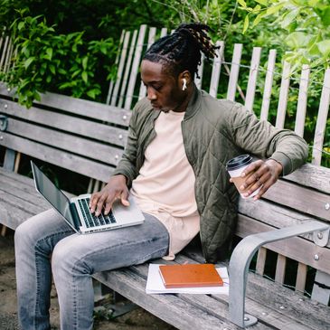 Man working on laptop outdoors with coffee.