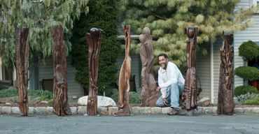 Randolph is surrounded by the larger sculptures in the collection  All made from black walnut. 