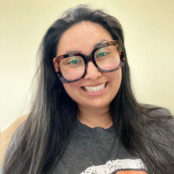 Smiling woman with long dark hair and large tortoiseshell glasses.