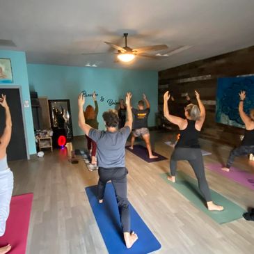 A group of people practicing yoga in a studio, featuring various poses and a calming environment.