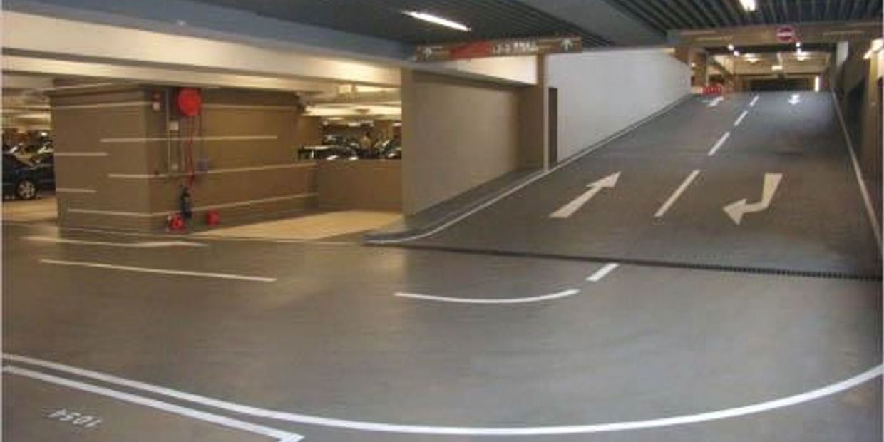 Empty indoor parking garage with directional arrows and a ramp.