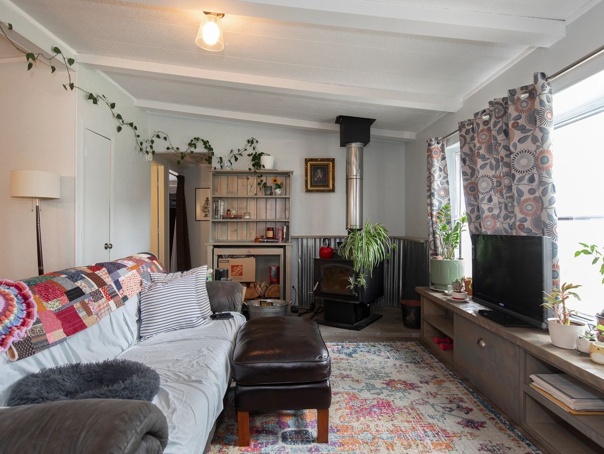 Cozy living room with a patchwork quilt, wood stove, and vibrant patterned curtains.