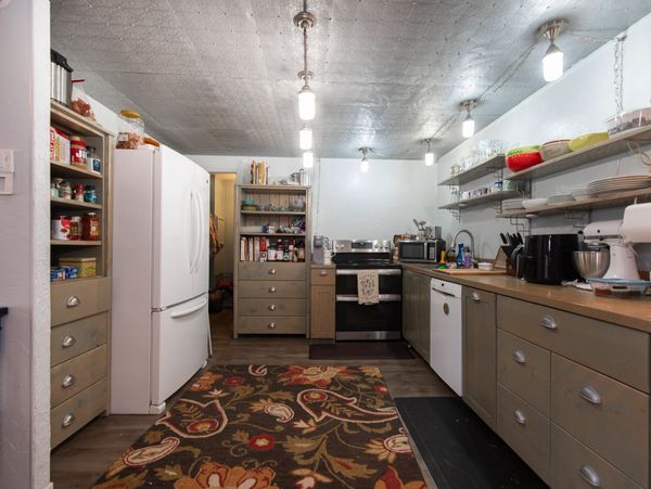 Cozy kitchen with warm lighting, wooden cabinets, and a floral rug.
