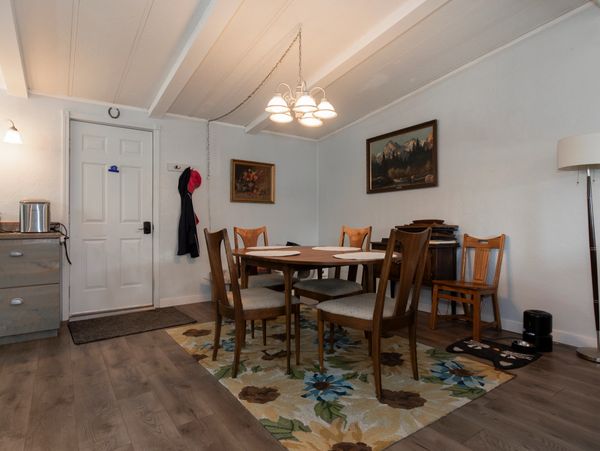 Cozy dining room with wooden chairs and floral rug under a modern chandelier.