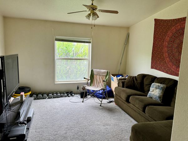 Cozy living room with a brown couch, folding chair, and TV setup.