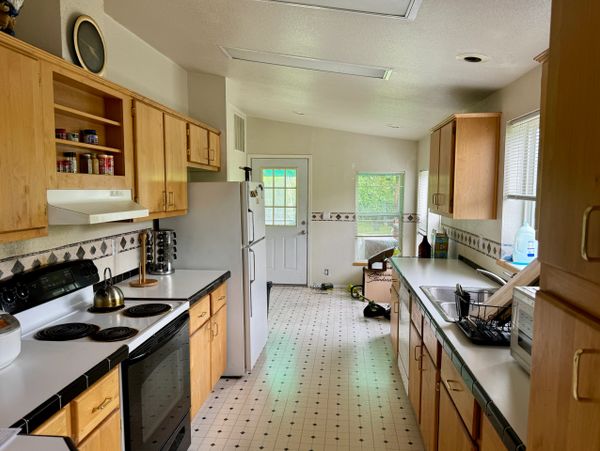 A clean kitchen with wooden cabinets, white appliances, and a tiled floor.