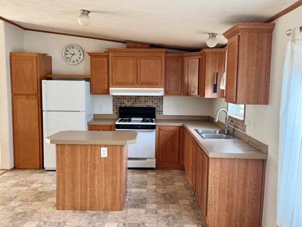Cozy kitchen with wooden cabinets, a small island, and white appliances.