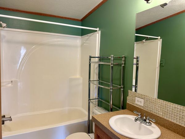 Bathroom with green walls, white bathtub, and a sink with a mirror.