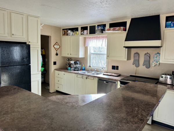 Modern kitchen with cream cabinets, black appliances, and a brown countertop.