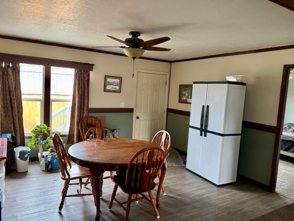 Cozy dining area with wooden table, chairs, and a modern white refrigerator.