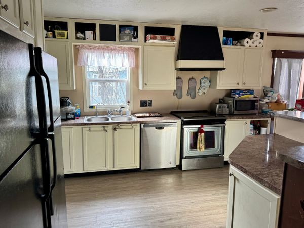 A neat kitchen with cream cabinets, stainless steel appliances, and a window above the sink.