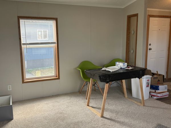 Minimalist room with two green chairs and a simple table covered in black plastic.