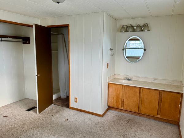 Empty room with carpet, vanity, and open door to bathroom.