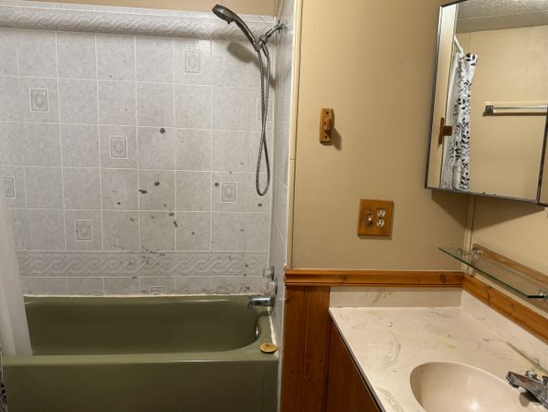 Old bathroom with green bathtub and beige sink.