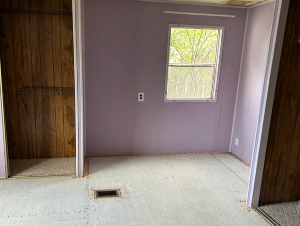 Empty room with purple walls and wood panel doors.