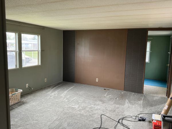 Empty room with brown accent wall and gray carpet.