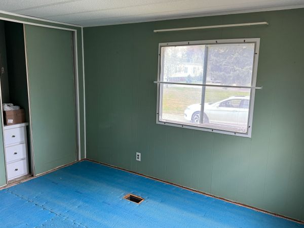 Empty room with green walls, a window, and blue floor covering.