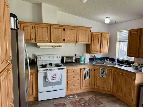Cozy kitchen with wooden cabinets, white appliances, and a variety of small kitchen items.