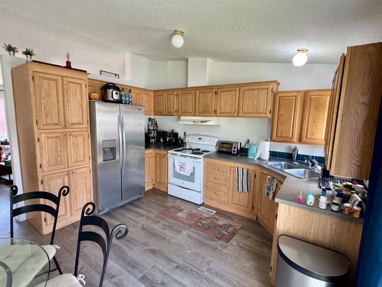 Cozy kitchen with wooden cabinets, stainless steel fridge, and a white stove.