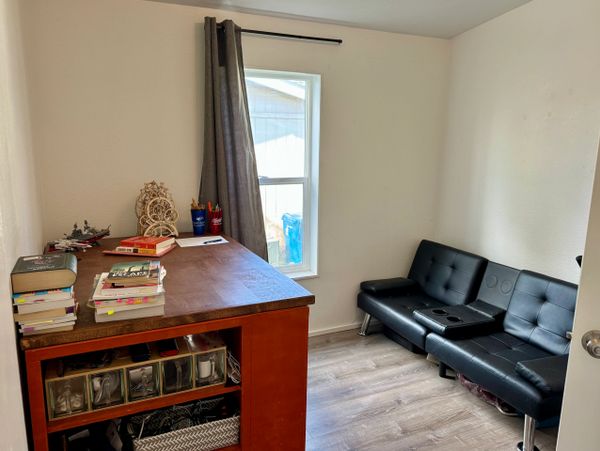 Small office with black couch, wooden desk, and books.