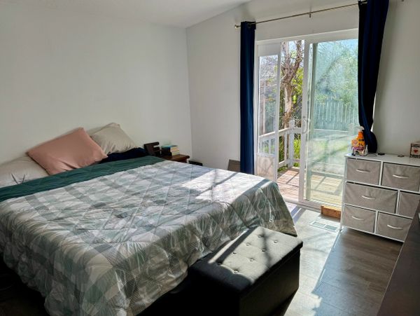 Sunlit bedroom with a large bed and sliding glass doors leading outside.