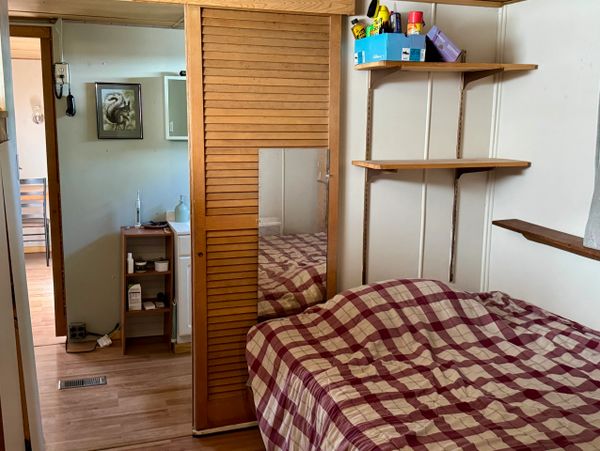 Small bedroom with checkered bedspread and wooden shelves.