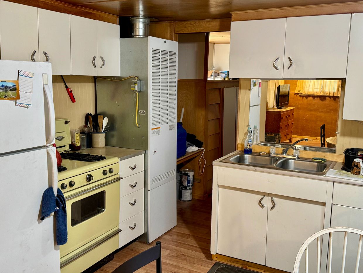 Cozy vintage kitchen with yellow stove and white cabinets.