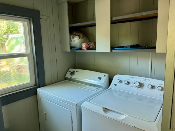 Laundry room with washer and dryer below shelves.