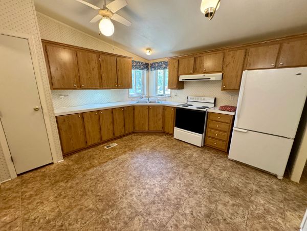 Spacious kitchen with wood cabinets and white appliances.