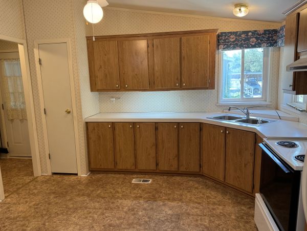 Empty kitchen with wood cabinets and white countertops.