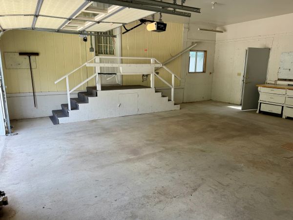 Empty garage space with stairs and utility area.