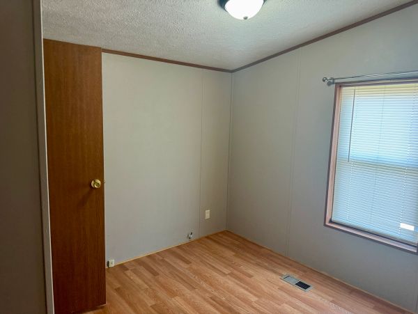 Empty room with wooden floor and window blinds.