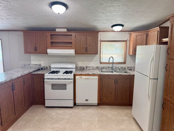 Kitchen with wooden cabinets and white appliances.