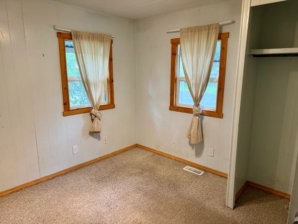 Empty room with two windows and beige curtains.