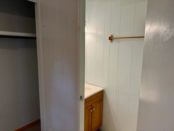 Partially open door revealing bathroom vanity and towel rack.