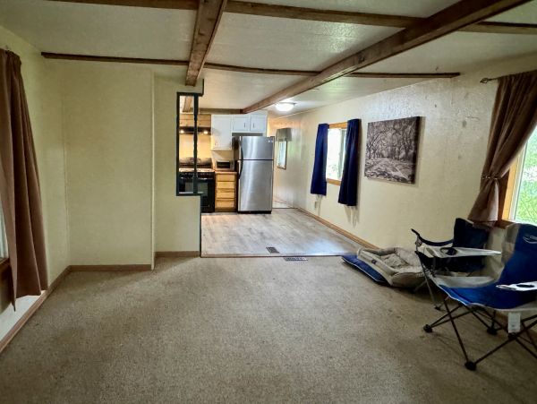Empty living room with kitchen in the background.