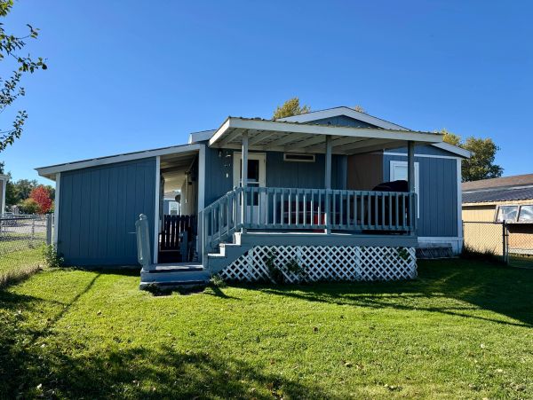 Blue house with a porch in a sunny yard.