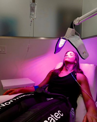A woman undergoing a red light therapy session in a clinical setting.