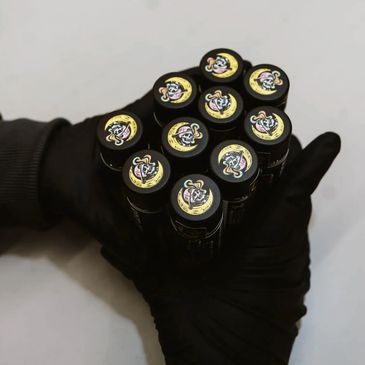 Gloved hands holding a cluster of black tubes with colorful cartoon snake logos.