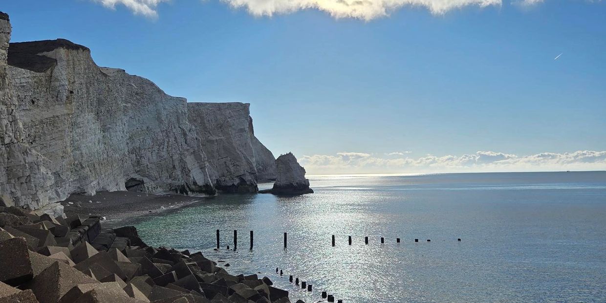 Cliffs by the calm sea under a clear sky.