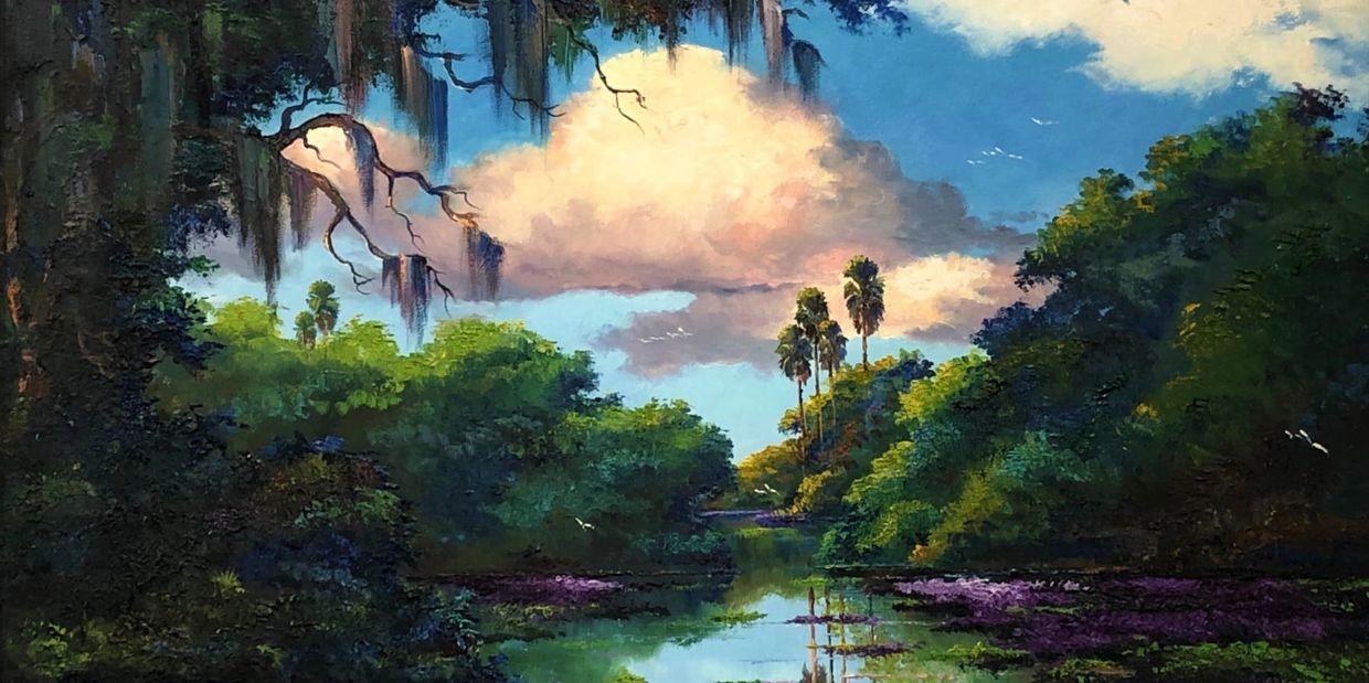 idyllic calm stream with purple lily pads, palm trees, and spanish moss hanging from foreground tree