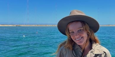 Young woman smiling on a boat with blue water and sky.