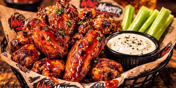 Crispy sauced wing monster chicken wings in a basket, served with dipping sauce.