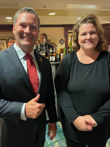 Two people smiling indoors, one giving a thumbs-up.