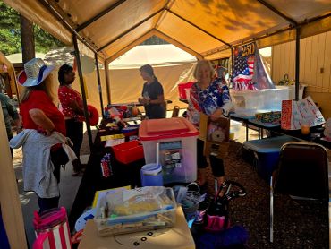 People shopping at an outdoor tent sale with American-themed decor.
