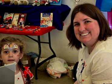Woman and child with face paint at an indoor event.