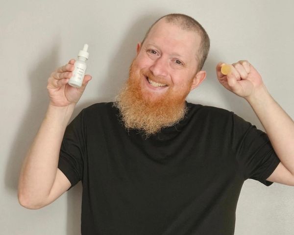 Smiling man holding skincare bottles.
